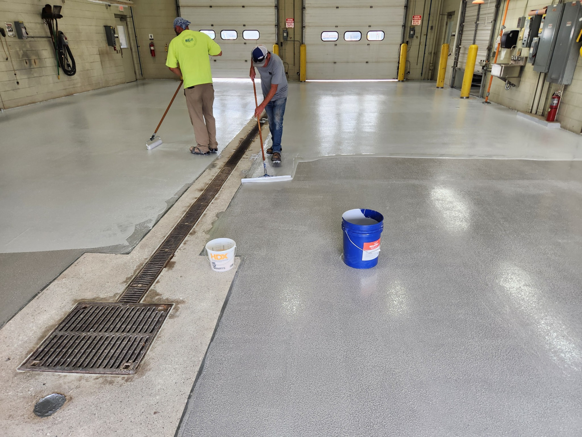 In progress — weld shop: the crew applying Belzona 5231 at 6 mils with rollers, working in from the drain channel.