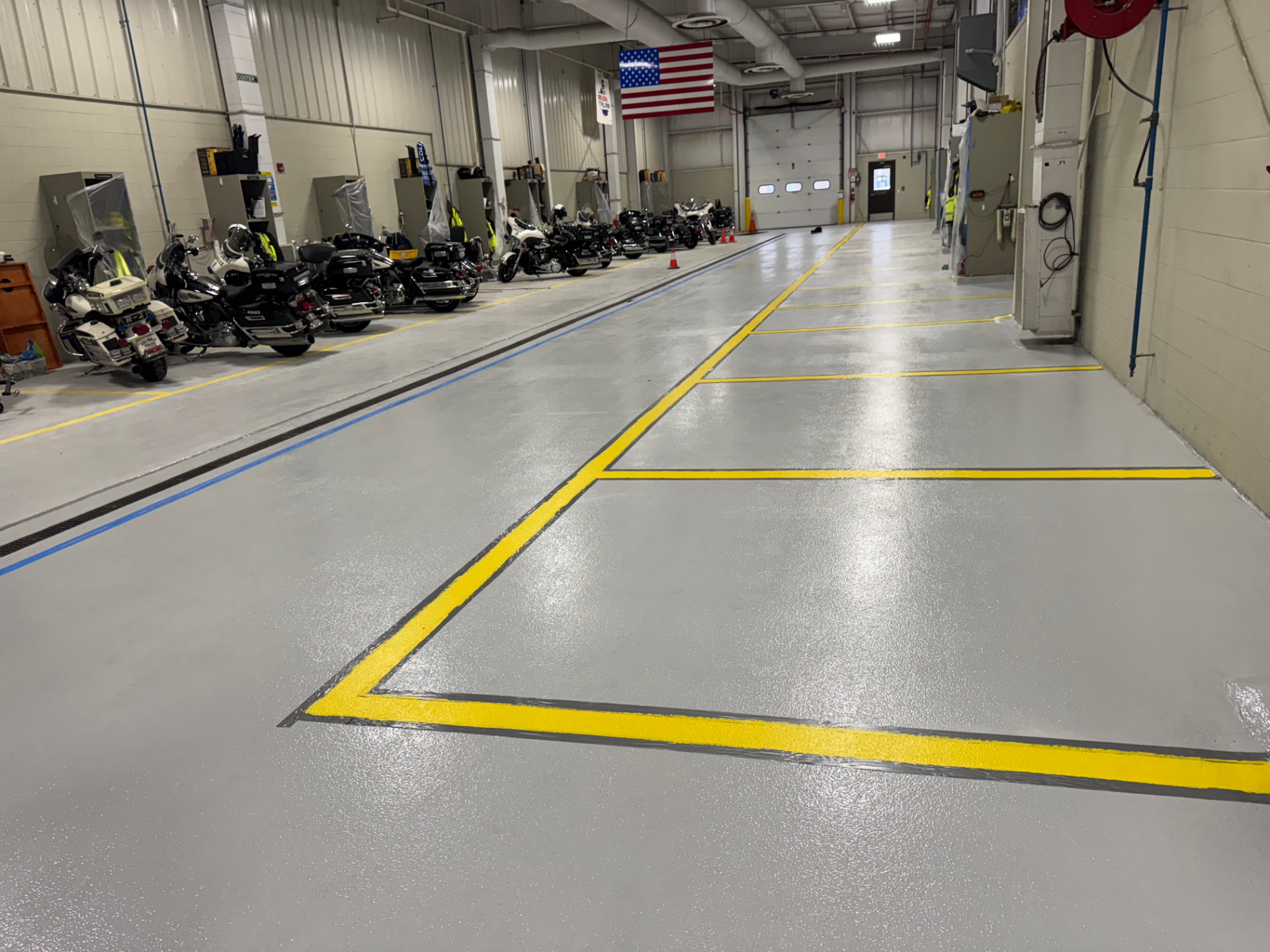 After — motorcycle bay: coated floor with fresh safety-yellow bay markings and a blue traffic line.