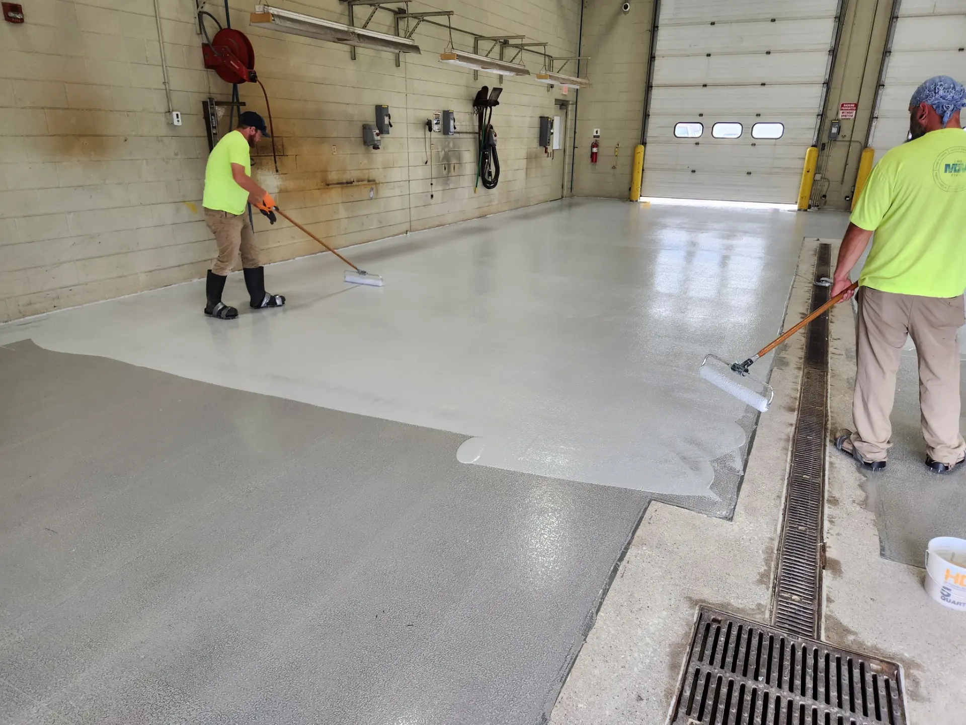 Crew rolling a Belzona floor coating across a facility bay