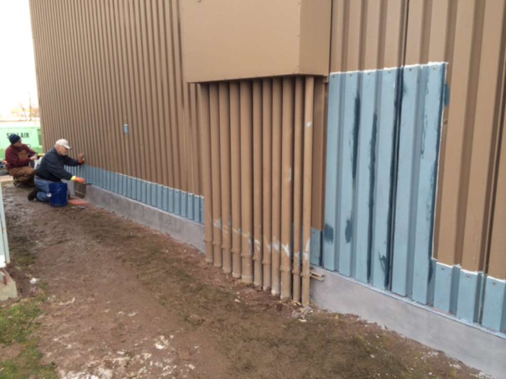 In progress: siding edges rebuilt and coated along a long wall, with the base resurfaced.