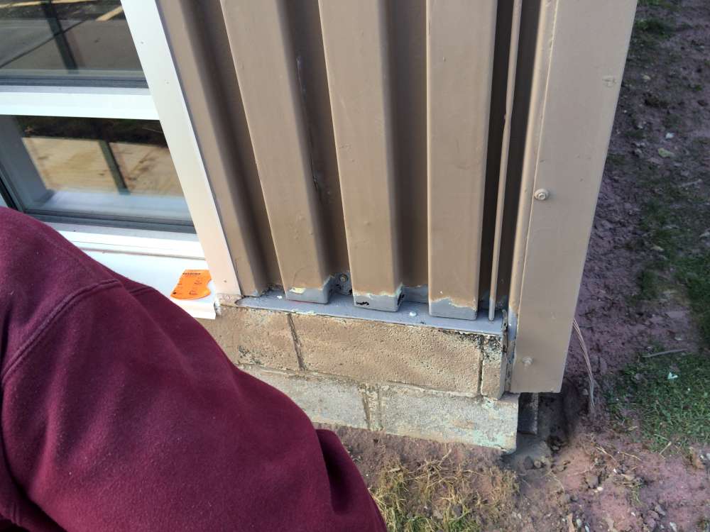 Before: deteriorated panel edges and block base at a corner next to a window.