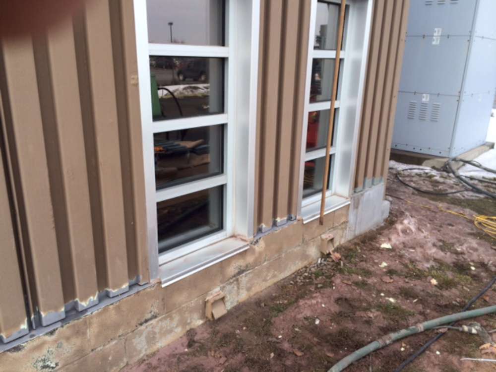 Before: damaged siding and a stained, spalled block base below the windows.