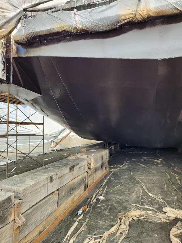 Black topcoat applied over the base coat at the bow.