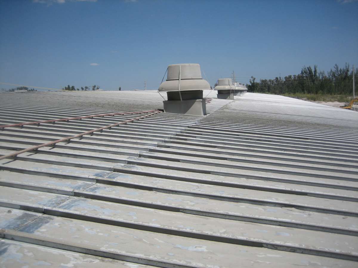 Before: the standing-seam metal roof over the packing area, with worn coating along the seams and vents.