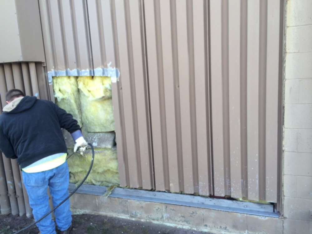 Siding removed, exposing the wall insulation behind the damaged panels.