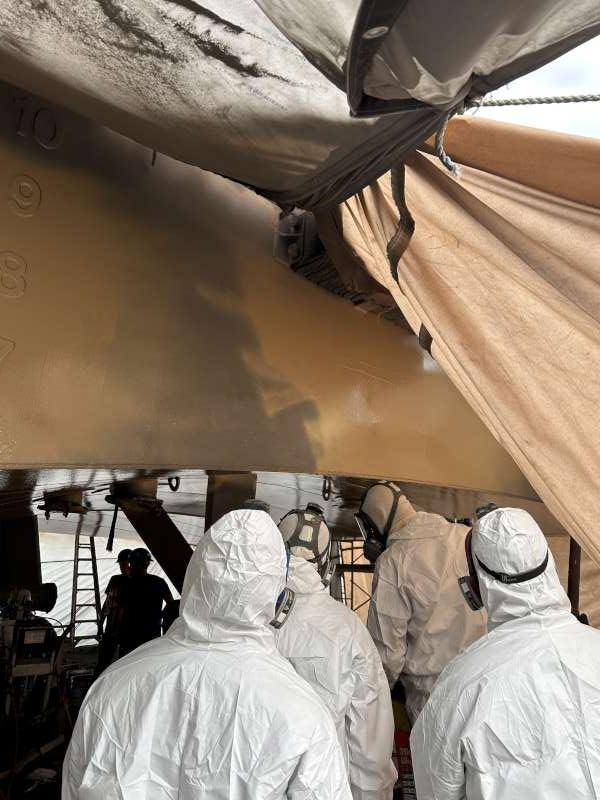 Crew spraying the Belzona 5811 beige base coat in full PPE.