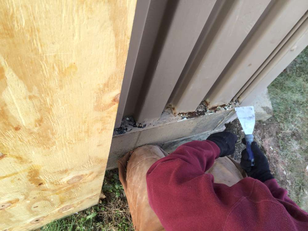 Surface prep: clearing debris and corrosion from the base of the siding.