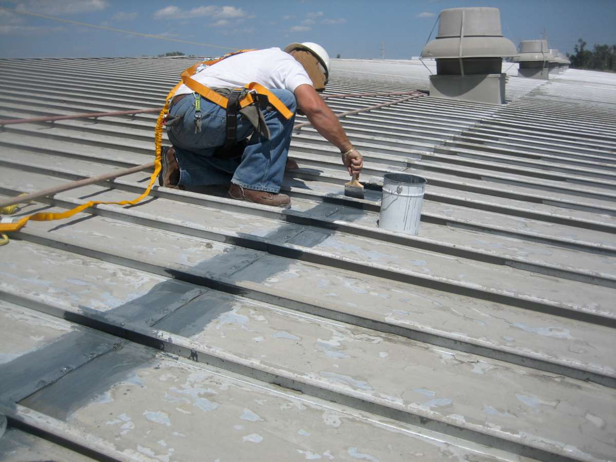 Technician brushing Belzona coating onto metal roof seams